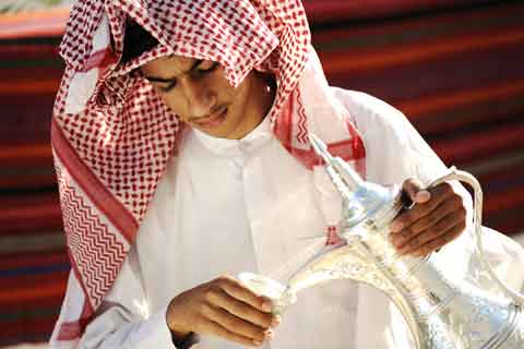 Un árabe del Golfo recibe invitados y sirve café de una cafetera dallah