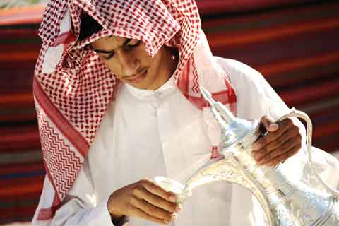 Gulf Arab receiving guests, pouring coffee from a dallah pot